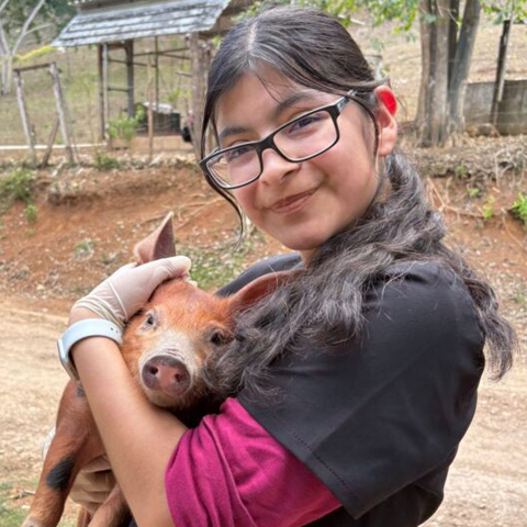 Gilman scholar holding a piglet